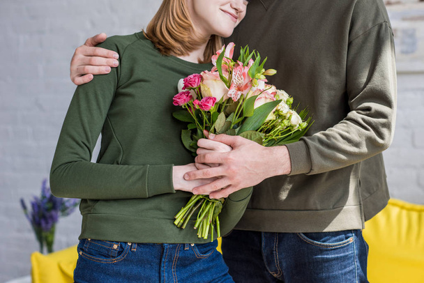 imagen recortada del hombre abrazando novia sonriente con flores
 - Foto, Imagen