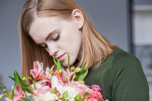 attractive young woman sniffing bouquet of flowers  - Photo, Image