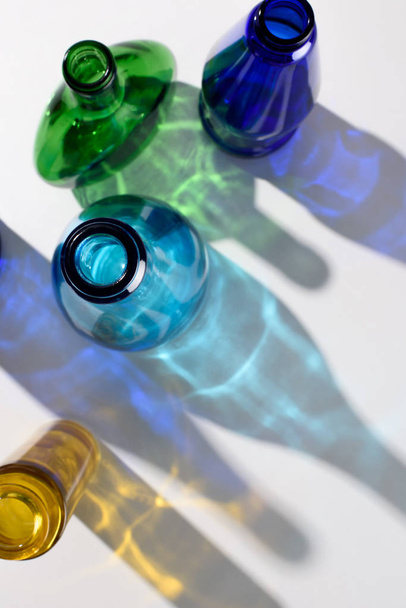 vista dall'alto di bottiglie di vetro colorate vuote sulla superficie bianca
 - Foto, immagini