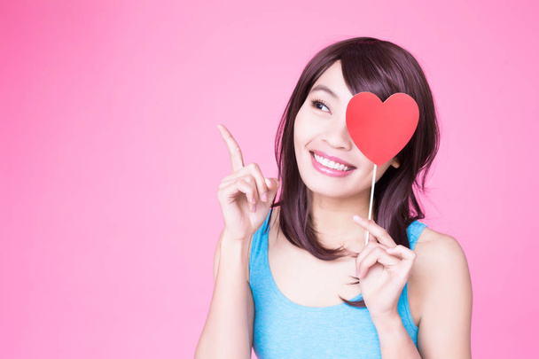 woman holding red love heart over eye on the pink background - Fotografie, Obrázek