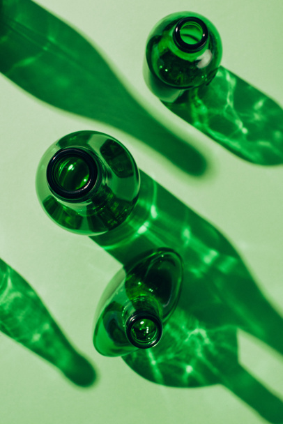 top view of arranged empty green glass bottles with shadows on tabletop - Photo, Image
