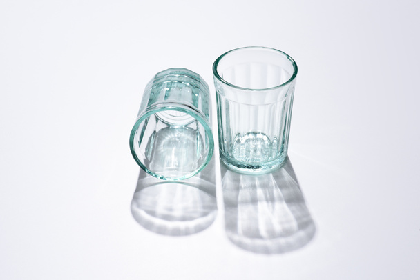 vista de cerca de vasos vacíos y sombras en la superficie blanca
 - Foto, Imagen