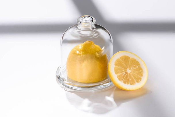 Nahaufnahme von frischer Zitrone im Glas auf weißer Tischplatte - Foto, Bild