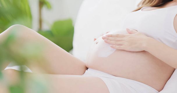 Nahaufnahme einer Creme gegen Dehnungsstreifen auf dem Bauch einer Schwangeren - Foto, Bild