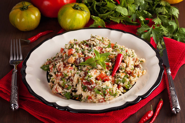 Tabbouleh - Middle Eastern vegetarian dish with couscous, tomatoes, parsley, dried raisins and mintseasoned with olive oil and lemon juice. Easy authentic recipe  - Photo, Image
