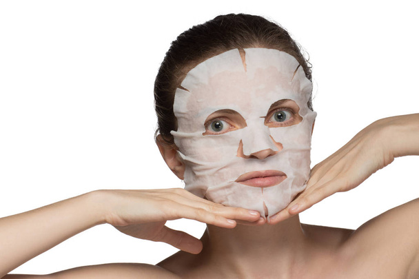 Hermosa joven está aplicando una máscara cosmética en una cara en un
 - Foto, Imagen