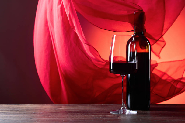 Gözlük ve rede şarap kırmızı bir arka plan üzerinde.  - Fotoğraf, Görsel