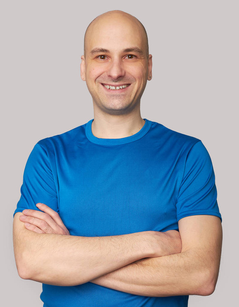 usmívající se holohlavý muž nosí modré tričko - Fotografie, Obrázek