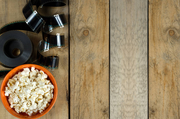 The coils of the film strip on wooden background with popcorn - Zdjęcie, obraz