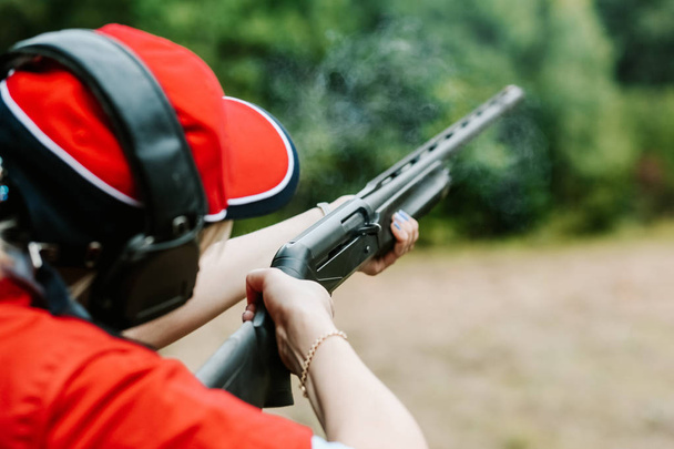 woman shooter headphones shoots hunting rifle smoke shot - Foto, immagini