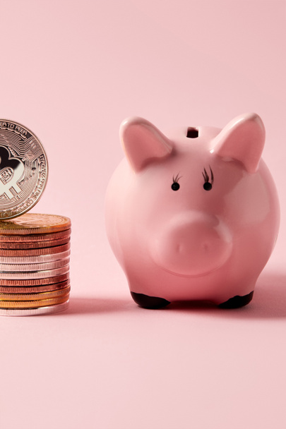 close-up shot of stack of bitcoins and piggy bank on pink tabletop - Fotó, kép