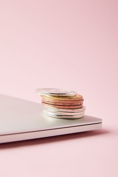 close-up shot of bitcoins stacked on closed laptop on pink surface - Zdjęcie, obraz