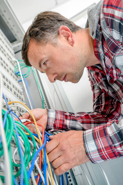 Man checking server wiring - Foto, afbeelding