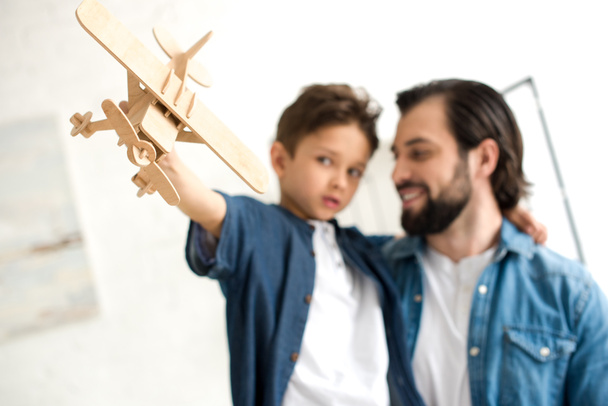 close-up view of father and son playing with wooden toy plane - Фото, изображение