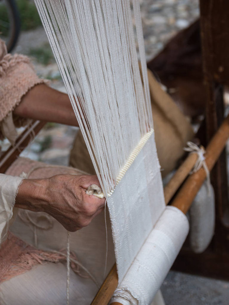 Las manos de la anciana tejiendo el patrón blanco en el antiguo telar de madera
 - Foto, Imagen
