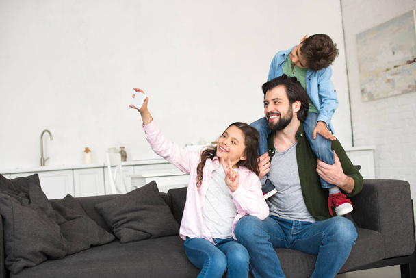 père heureux avec deux enfants adorables prenant selfie avec smartphone à la maison
 - Photo, image