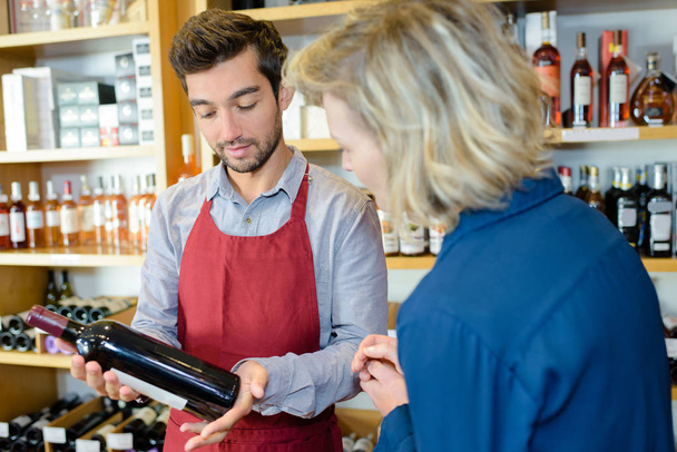 Wine merchant recommending bottle to customer - Foto, Imagem