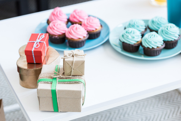 cupcakes rosas y azules y cajas de regalo en mesa blanca, concepto de fiesta de bebé
 - Foto, imagen