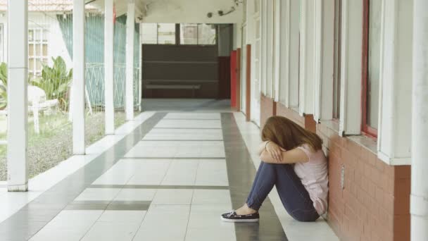 Acoso escolar. Mujer adolescente molesto sentado en el pasillo de la escuela
. - Imágenes, Vídeo