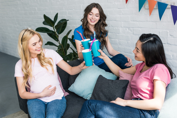 multikulturní přátelé a těhotná žena cinkání s nápoji v papírových kelímků na dětské párty - Fotografie, Obrázek