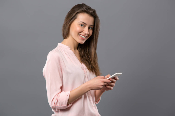 Joyful young woman using her smartphone - Zdjęcie, obraz