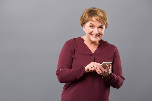 Joyful nice woman using her smartphone - Фото, изображение