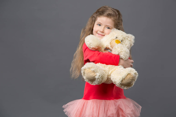 Delighted cute girl hugging her fluffy bear - Fotoğraf, Görsel