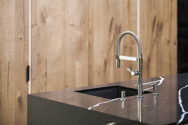 Kitchen faucet, modern kitchen in loft style, black marble table, wooden luxury kitchen - Foto, immagini