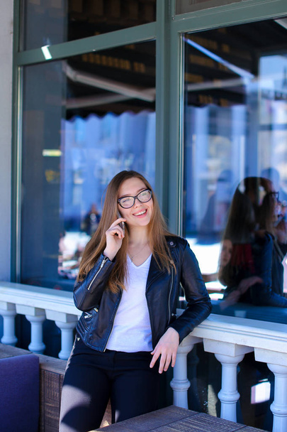Leuke vrouw in glazen spreken door de smartphone op straat Cafe. - Foto, afbeelding
