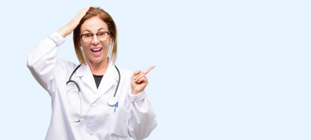Γυναίκα γιατρός, ιατρική επαγγελματική δείχνει μακριά πλευρά με το δάχτυλο απομονωμένη μπλε φόντο - Φωτογραφία, εικόνα