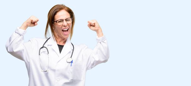Kobieta lekarz, medyczne szczęśliwy i podekscytowany świętuje zwycięstwo wyrażając wielki sukces, mocy, energii i pozytywnych emocji. Świętuje Nowy zadanie radosny na białym tle niebieskim tle - Zdjęcie, obraz