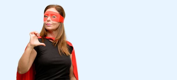 Medioevo donna super eroe indossando maschera rossa e mantello orgoglioso, eccitato e arrogante, che punta con la faccia vittoria isolato sfondo blu
 - Foto, immagini