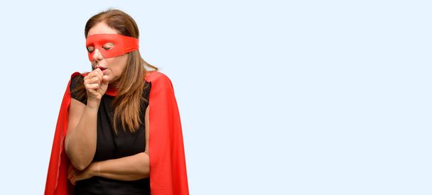 中年スーパー ヒーロー女性赤のマスクとマント病気を身に着けていると咳、喘息や気管支炎、医学概念分離された青い背景に苦しんでいます。 - 写真・画像