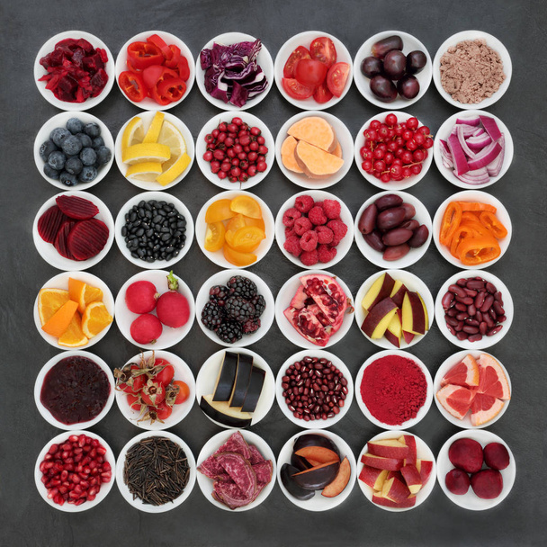 Healthy eating super food collection with fruit, vegetables, pulses and grains on slate background.  Foods very high in antioxidants, anthocyanins, minerals and vitamins promoting good health. Top view. - Photo, Image
