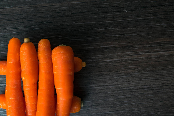 mini zanahorias crudas de naranja bebé en la mesa de madera oscura
 - Foto, imagen
