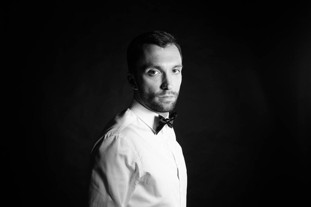 Studio portret van stijlvolle jonge man in een wit overhemd en een zwarte bo - Foto, afbeelding