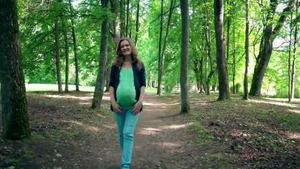 νεαρή έγκυος γυναίκα περπατά μόνος στο πάρκο και εγκεφαλικά επεισόδια στην κοιλιά της - Πλάνα, βίντεο