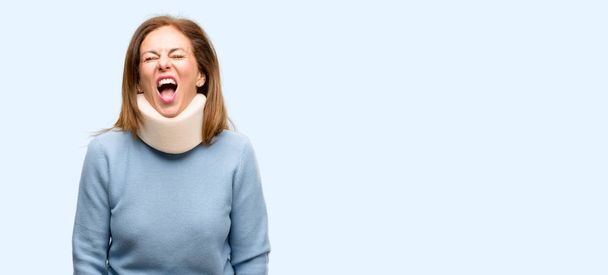 Mujer lesionada con cuello ortopédico cuello estresante, aterrorizada por el pánico, gritando exasperada y frustrada. Un gesto desagradable. El trabajo molesto me vuelve loco fondo azul aislado
 - Foto, imagen