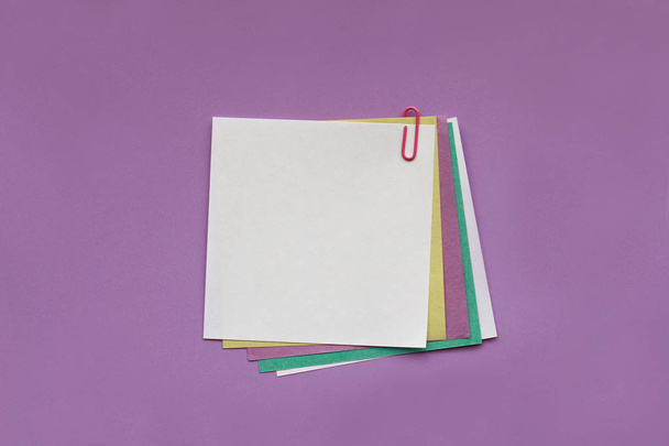 Etiqueta de papel de nota en blanco con clip sobre fondo púrpura
 - Foto, Imagen