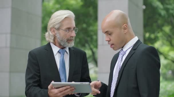 два руководителя корпораций обсуждают бизнес с помощью цифрового планшета
 - Кадры, видео