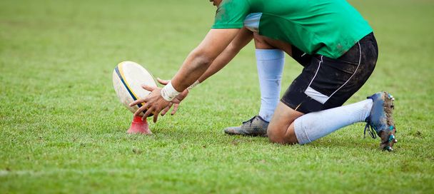jugador de rugby se prepara para patear la pelota ovalada durante el juego
 - Foto, Imagen