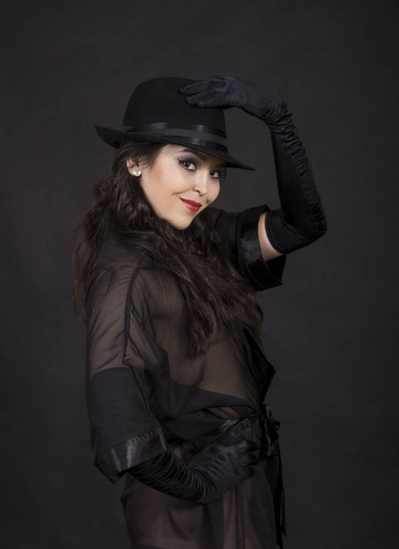 Beautiful young girl in black tunic, black gloves and black hat. - Фото, зображення