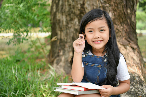 Концепции образования. Девушка читает книгу в саду. Be
 - Фото, изображение
