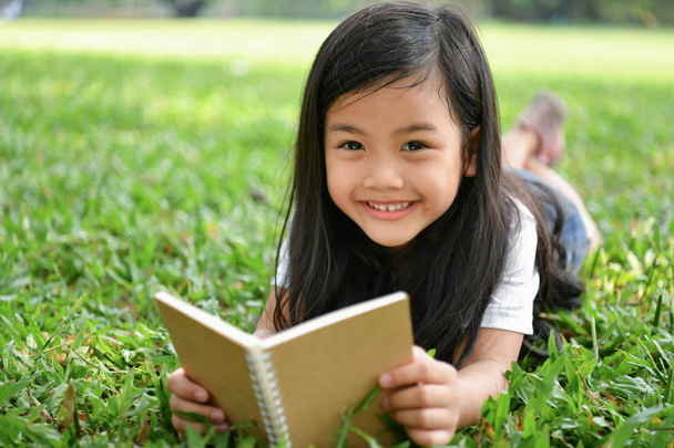 Koncepcje edukacji. Dziewczyna jest z książką w ogrodzie. Być - Zdjęcie, obraz