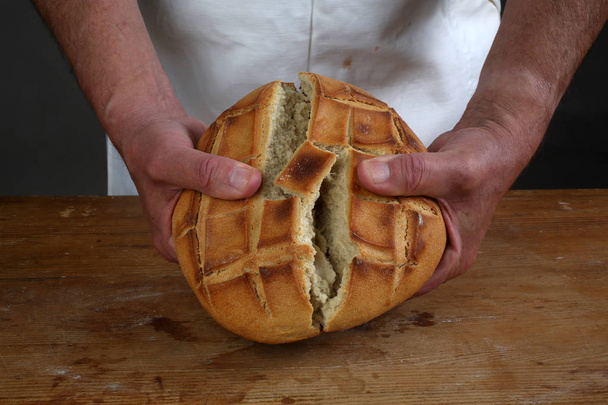 Breaking of a fresh loaf of Eucharistic bread. - Photo, Image