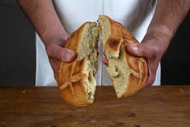 Breaking of a fresh loaf of Eucharistic bread. - Photo, Image