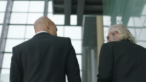 Achteraanzicht van twee collectieve stafmedewerkers chatten terwijl oplopende trap in bedrijf. - Video