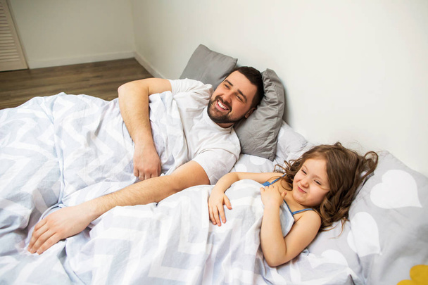 Dad and daughter have fun at home on the bed. Father's Day. - Foto, imagen