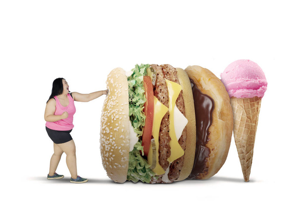 Obese woman fights with unhealthy foods on studio - Foto, Imagen