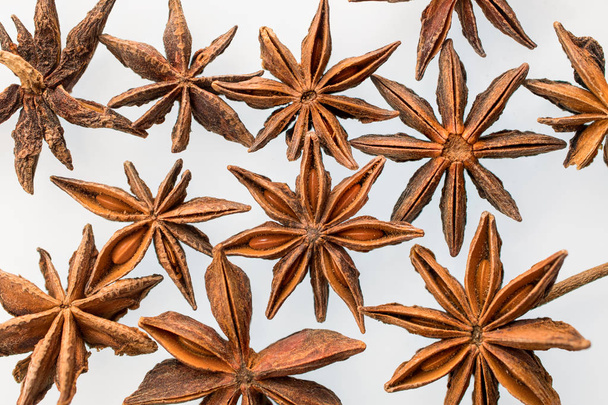 Vagens de sementes de anis estrelado dispostas em um fundo branco
 - Foto, Imagem